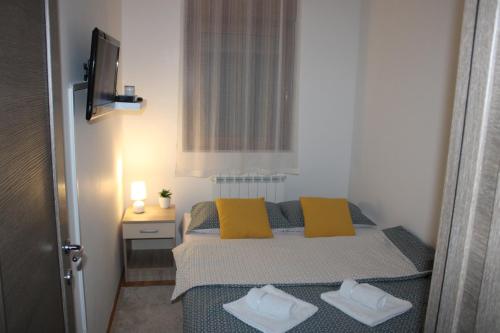 een kleine slaapkamer met een bed met 2 gele kussens bij Apartman Goca in Zlatibor