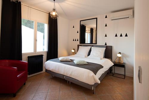 a bedroom with a bed with a mirror and a red chair at Mise en Scène in Aumelas