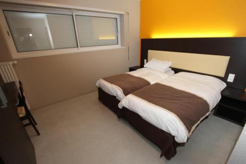 a bedroom with a large bed with a window at Les Portes d'Apcher in Saint-Chély-dʼApcher