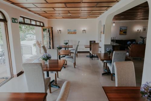 a restaurant with wooden ceilings and tables and chairs at Cana Vineyard Guesthouse in Paarl