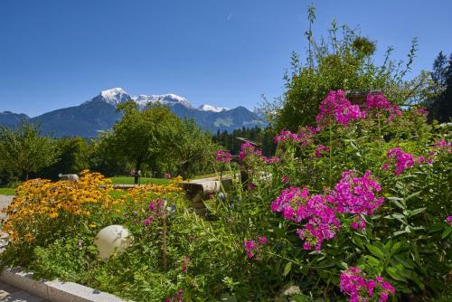 a garden with flowers and mountains in the background at Alpenhotel Hundsreitlehen in Bischofswiesen