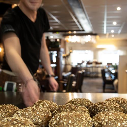 a man standing in a bakery with a pile of bread at Hotel Restaurant 'de Vossenberg' in Vierhouten