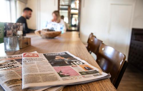a newspaper sitting on top of a wooden table at Hotel Restaurant 'de Vossenberg' in Vierhouten