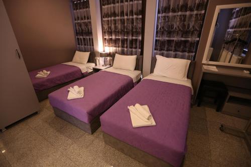 a room with three beds with white and purple sheets at Hotel Korzo in Bitola