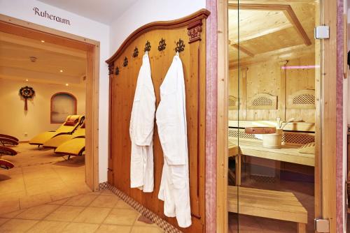 a dressing room with white shirts hanging on a door at Alpenhotel Hundsreitlehen in Bischofswiesen