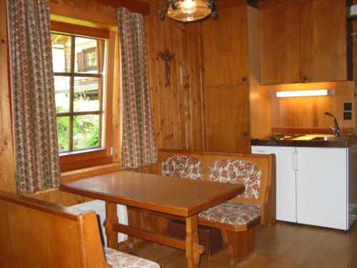 cocina con mesa de madera, sillas y ventana en Ferienhaus Wassermühle, en Maria Luggau