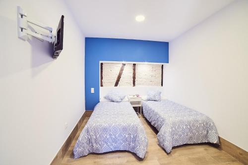 due letti in una stanza con pareti blu di La Balconada de Toledo - PARKING GRATIS - 2 HABITACIONES a Toledo