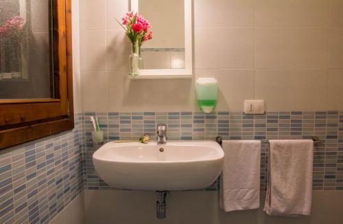 un lavandino in bagno con asciugamani e un vaso con fiori di GF Apartments La Vigna a Badesi