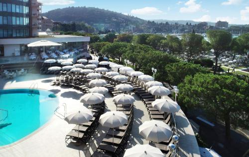 a group of white umbrellas sitting next to a pool at Hotel Slovenija - Terme & Wellness LifeClass in Portorož
