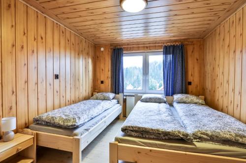 two beds in a room with wooden walls at Domek na Zagroniu in Istebna