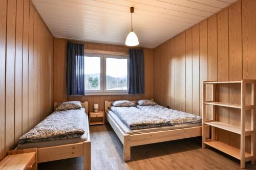 two beds in a room with wooden walls at Domek na Zagroniu in Istebna