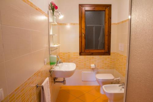 a bathroom with a sink and a toilet and a mirror at GF Apartments La Vigna in Badesi