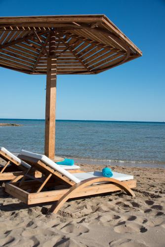 a pair of chairs and an umbrella on a beach at Shams Prestige Abu Soma (Adults Only) in Hurghada