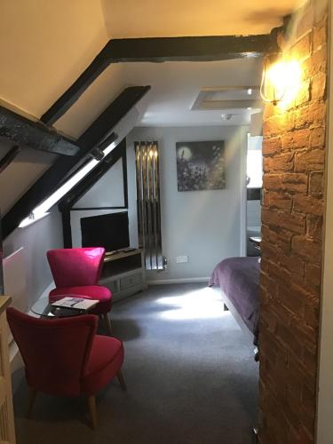 a room with a bed and chairs and a tv at Anglebury House in Wareham