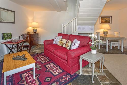 a living room with a red couch and a table at Stable Cottage in Enford