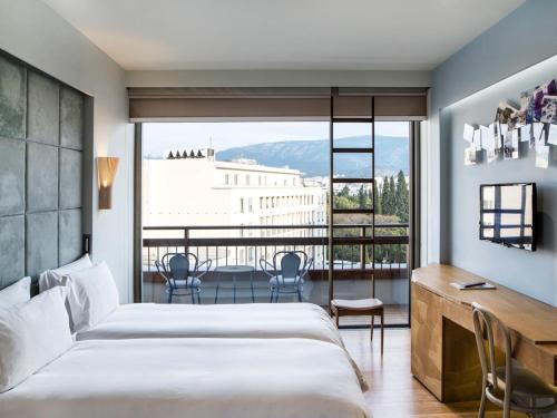 1 dormitorio con cama, escritorio y ventana grande en New Hotel, en Atenas