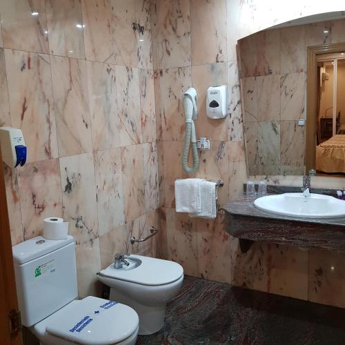 a bathroom with a toilet and a sink at Hostal La Parada in Pedro Muñoz