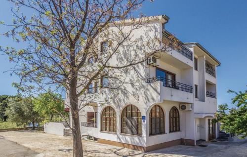 un edificio bianco con un albero di fronte di Rooms & Apartment Hegic a Zara (Zadar)