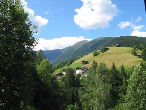 a green hillside with houses on a hill with trees at Unser kleines Bauernhaus in Maria Luggau