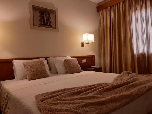 a bedroom with a large bed with a blanket on it at Hotel dos Loios in Santa Maria da Feira
