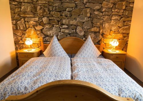a bedroom with a stone wall and a bed with two lights at Ferienhof Am Holderbusch in Füssen