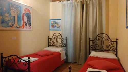 a bedroom with two beds with red sheets at AGRITURISMO MELOGRANO D'ORO in Bardolino
