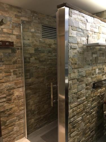 a shower in a bathroom with a stone wall at Bello Alojamiento Noa in Blanes