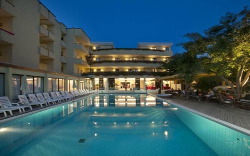 a swimming pool with chairs and a building at Park Hotel Kursaal in Misano Adriatico