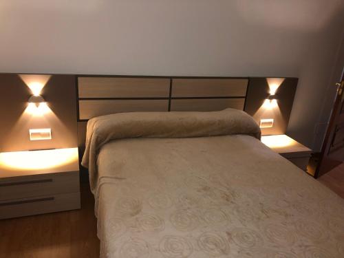 Un dormitorio con una cama con dos luces. en Apartamento Vistas al mar, en Foz
