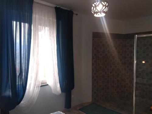 a bathroom with a window with blue curtains and a shower at Confort By The Sea in Vico Equense