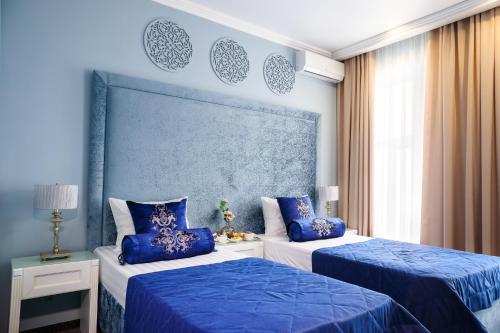two beds in a room with blue walls and blue pillows at Hotel Kaganat in Kazan