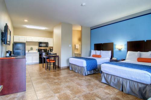 a hotel room with two beds and a kitchen at Alister Square Inn in Port Aransas