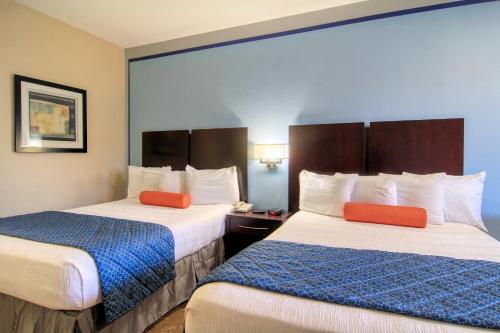a hotel room with two beds with orange pillows at Alister Square Inn in Port Aransas