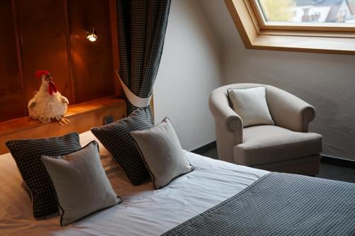 1 dormitorio con 1 cama, 1 silla y 1 pollo en Hôtel Le Riquewihr, en Riquewihr