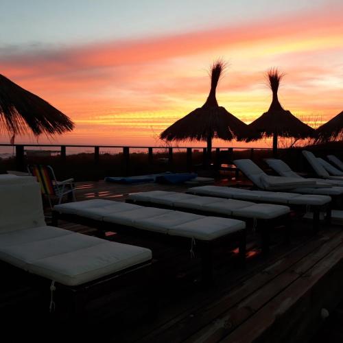 a group of lounge chairs and straw umbrellas at sunset at Las Eduardas in La Paloma
