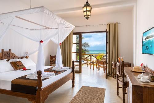 a bedroom with a bed and a balcony with the ocean at Next Paradise Boutique Resort in Pwani Mchangani