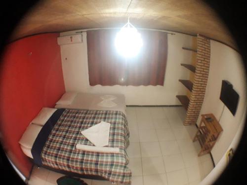 a small room with a bed and a light at Pousada Sena in Flecheiras