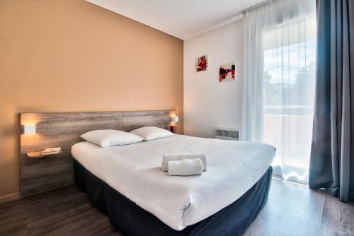 トゥールーズにあるゼニチュード オテル レジデンス トゥールーズ メトロポールの大きな窓付きの客室の大型ベッド1台分です。