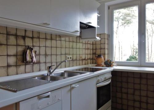 a white kitchen with a sink and a window at Ferienwohnung Kiefernblick-Wedemann in Bispingen