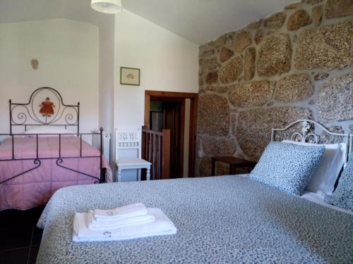 - une chambre avec 2 lits et un mur en pierre dans l'établissement Casas do Eido e Casa da Viúva, à Castelbuono