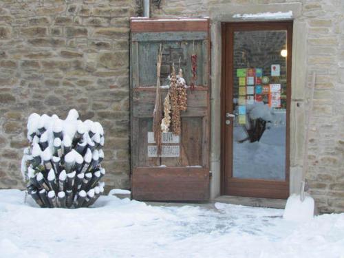 a door to a store with snow in front of it at La Locanda Della Campanara in Santa Sofia