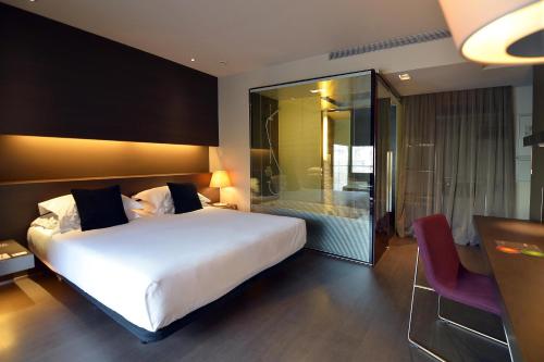 a bedroom with a large white bed and a glass walk in shower at Hotel Soho in Barcelona
