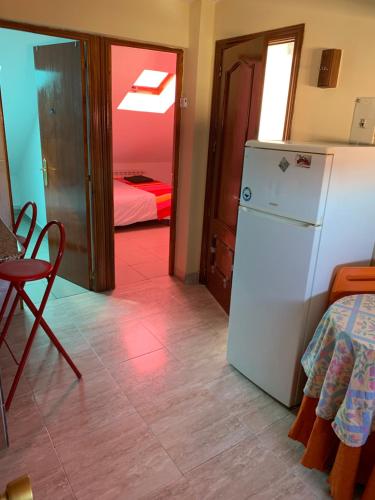 a kitchen with a refrigerator and a room with a bed at Atico plaza San Martín/plaza mayor in León