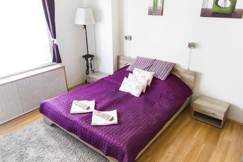 1 dormitorio con 1 cama morada y 2 toallas en Andy's Home Central Apatment, en Budapest