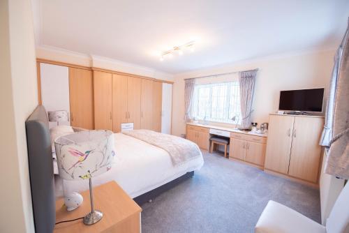 een slaapkamer met een bed, een bureau en een televisie bij Riseden Bed and Breakfast in Maidstone