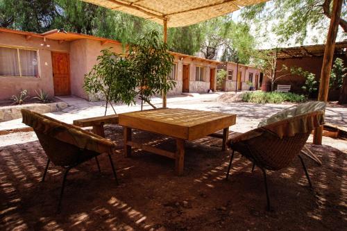 uma mesa de madeira e duas cadeiras num quintal em Quinta Adela Bed & Breakfast em San Pedro de Atacama