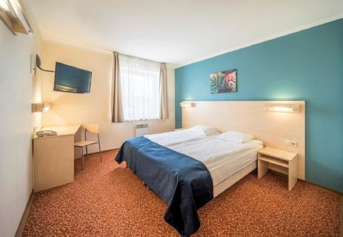 a bedroom with a bed and a desk and a television at Rija Bauska Hotel in Bauska