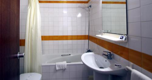 a bathroom with a sink and a tub and a toilet at Hotel Luar in Portimão