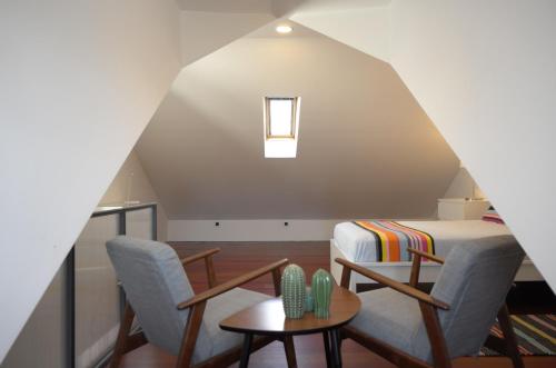 a attic room with a bed and two chairs and a table at 1881 Historical duplex Suite in Lisbon