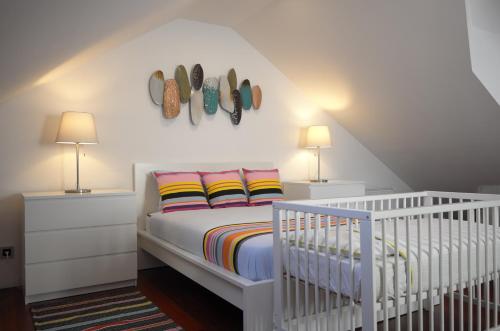 a white bedroom with a crib and two lamps at 1881 Historical duplex Suite in Lisbon